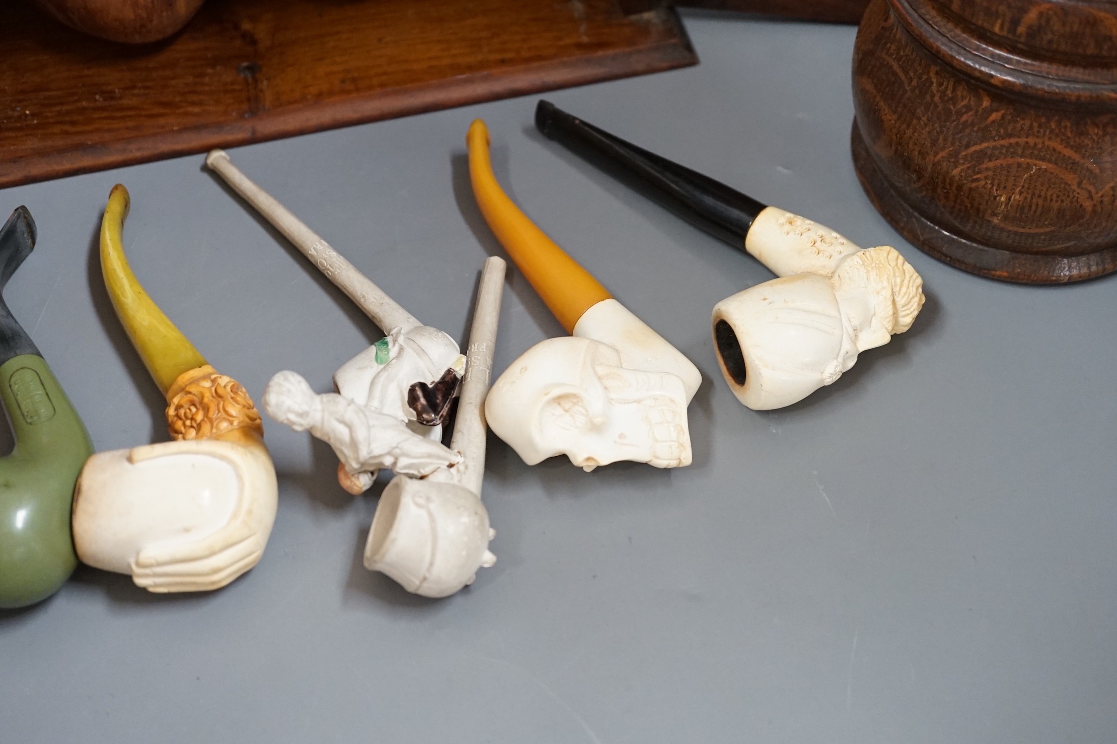 A carved smoker’s cabinet containing Meerschaum and other pipes and a tobacco jar, cabinet 25cm high